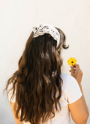 Back view of a white crochet bandana worn over long dark hair.