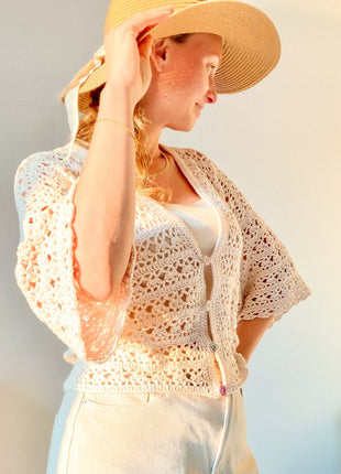 Profile view of a woman wearing the cream Magnolia Cardigan and a straw hat.