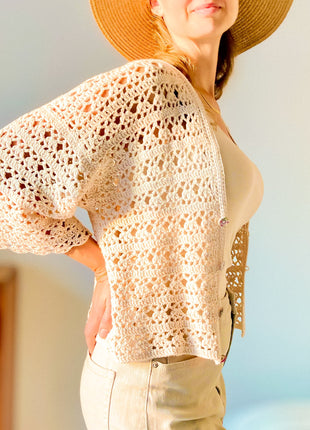 Side view of the cream Magnolia Cardigan showing the flared lace sleeve and open stitch texture.